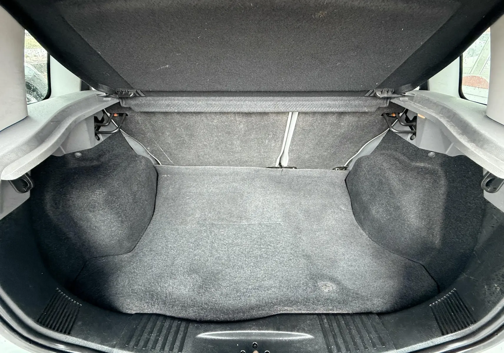 Coffre ouvert de la Ford Fusion 2002, vue intérieure montrant le revêtement gris et l'espace de rangement vide.