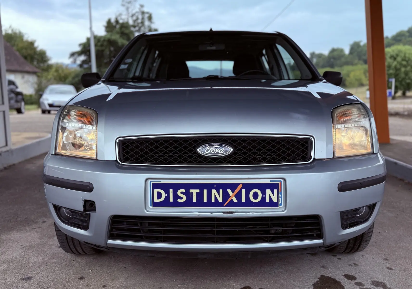 Vue frontale d'une Ford Fusion bleu clair avec phares allumés et plaque d'immatriculation Distinxion.