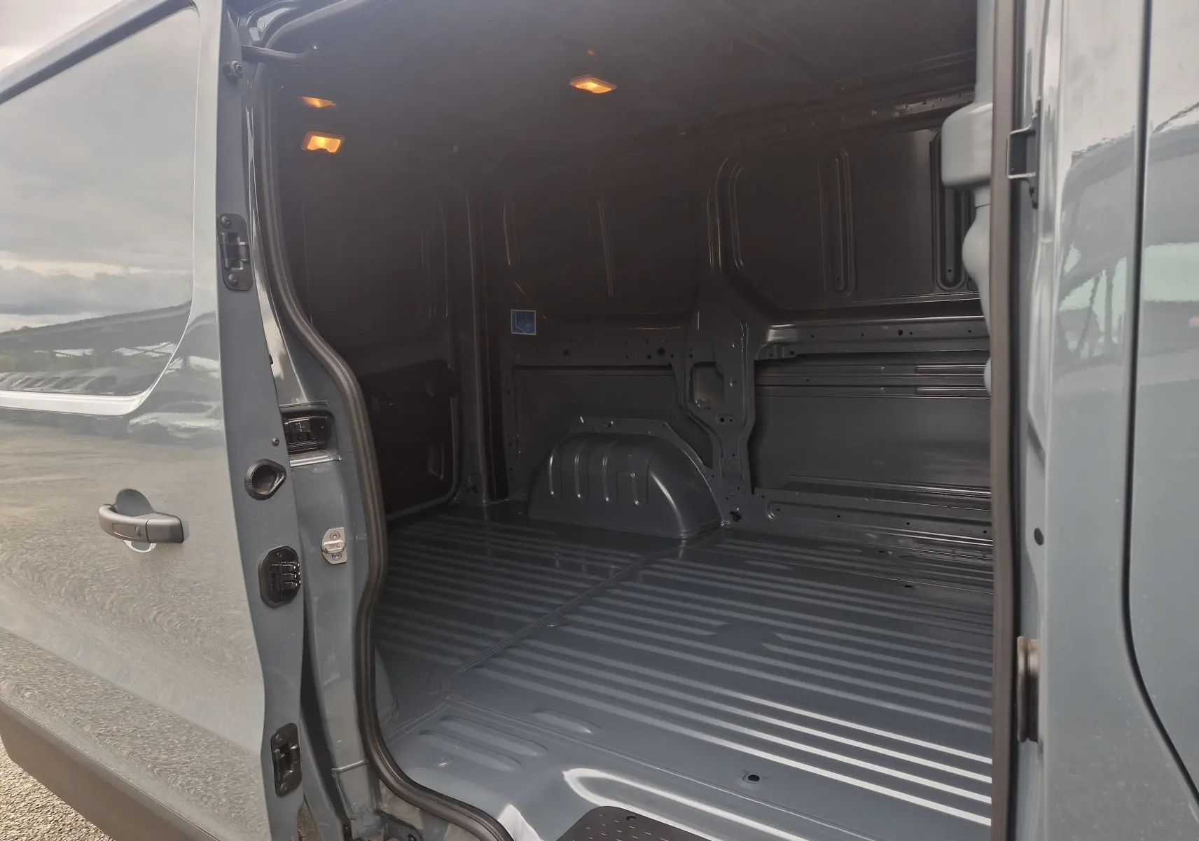 Vue intérieure du fourgon Renault Trafic L1H1 2025 gris urbain, montrant l'espace de chargement vide et éclairé.