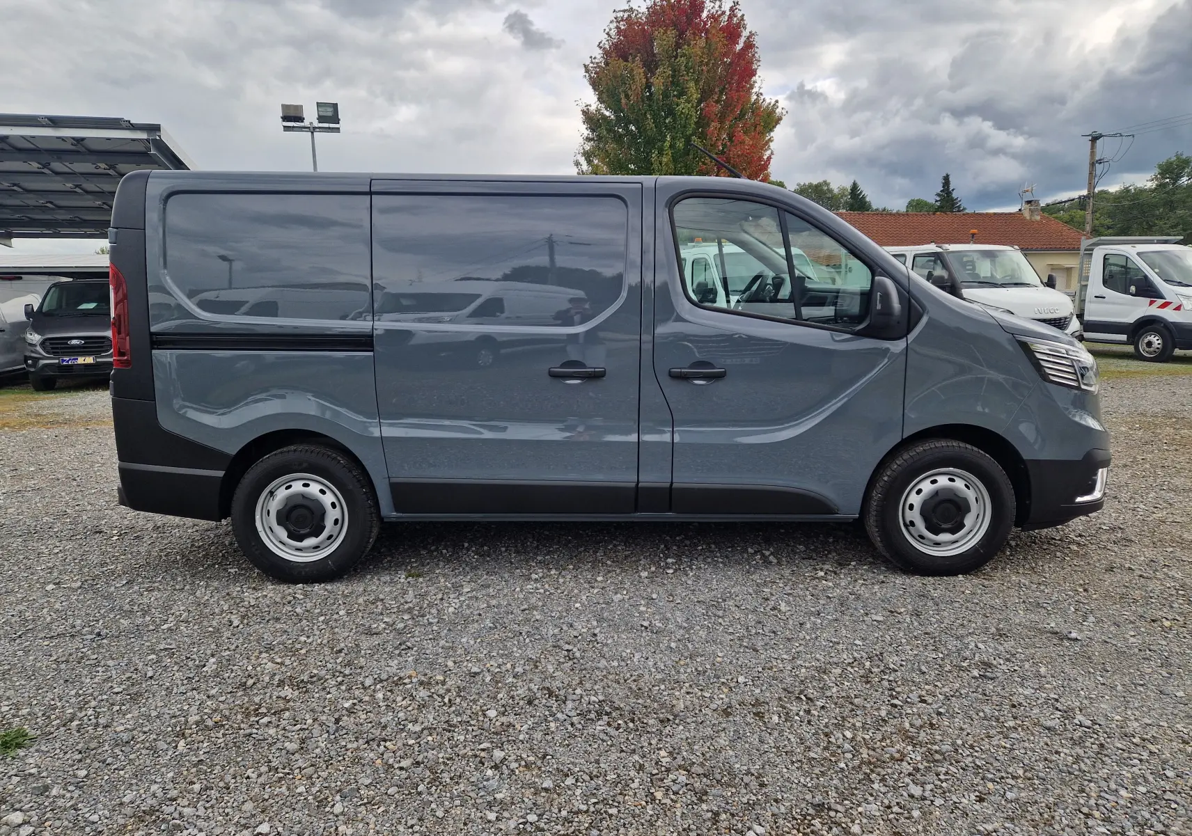 Profil droit du Renault Trafic Fourgon L1H1 2025 en gris urbain, avec jantes acier et carrosserie lisse sans fenêtres arrière.