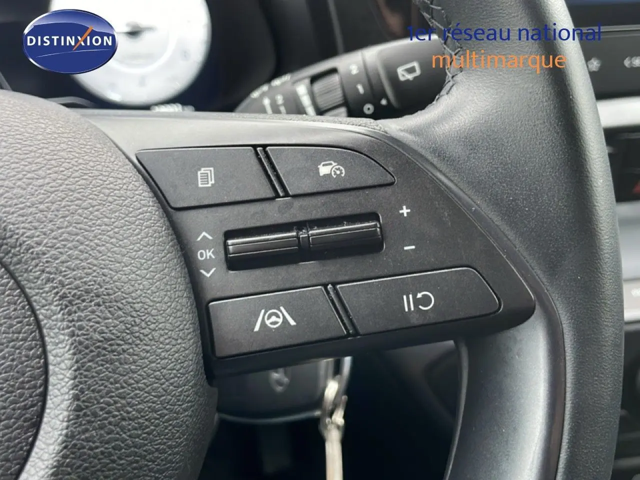 Gros plan sur les commandes au volant à droite d’une Hyundai i20 gris Aurora Metal, mettant en valeur les boutons de régulateur de vitesse.