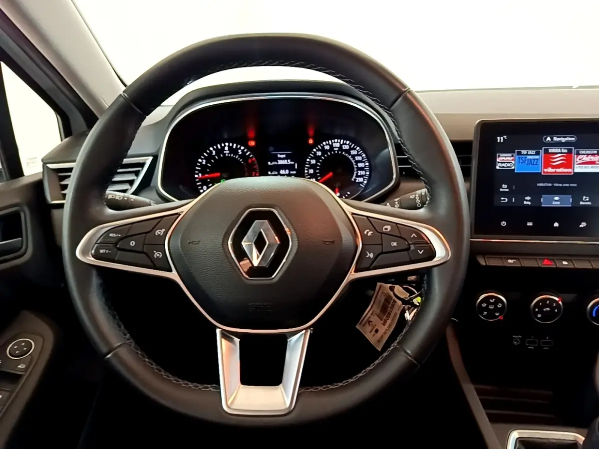 Vue rapprochée du volant cuir noir et du tableau de bord numérique de la Renault Clio Business blanche de 2021.