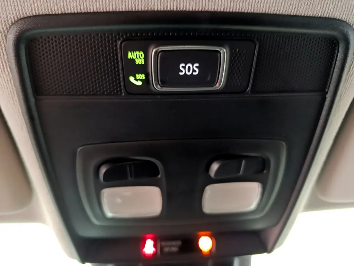 Vue en contre-plongée du plafonnier noir avec bouton SOS éclairé vert dans l'habitacle de la Renault Clio blanche 2021.