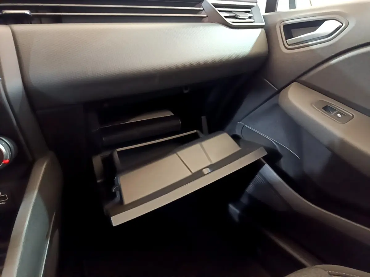 Intérieur de la Renault Clio Business blanche, vue côté passager avec boîte à gants ouverte et tableau de bord noir.