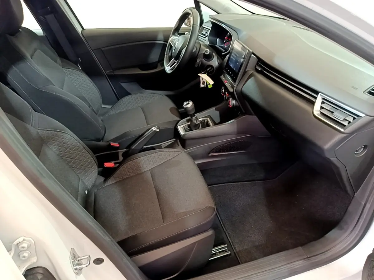 Intérieur de la Renault Clio Business blanc, vue côté conducteur, sièges tissu noir et tableau de bord moderne avec écran tactile.