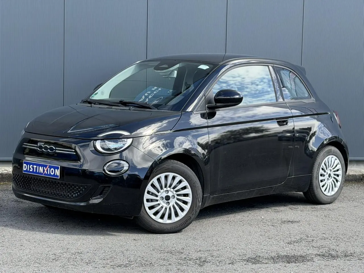 Fiat 500 électrique noir Onyx vue 3/4 avant droit, avec jantes blanches et calandre distinctive 500.