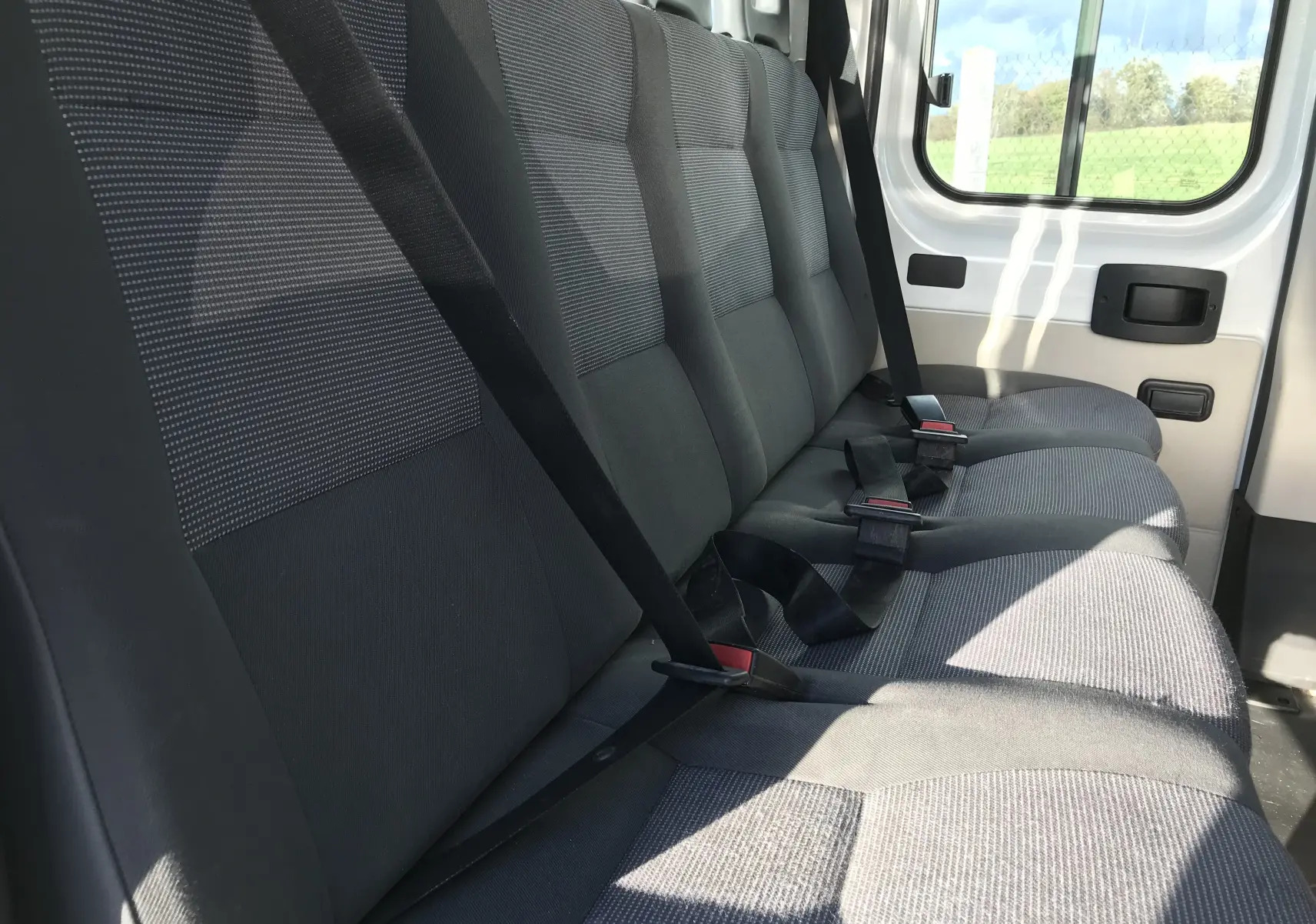 Banquette arrière grise vue de côté droit dans le Peugeot Boxer Châssis Double Cabine blanc 2014, 7 places.