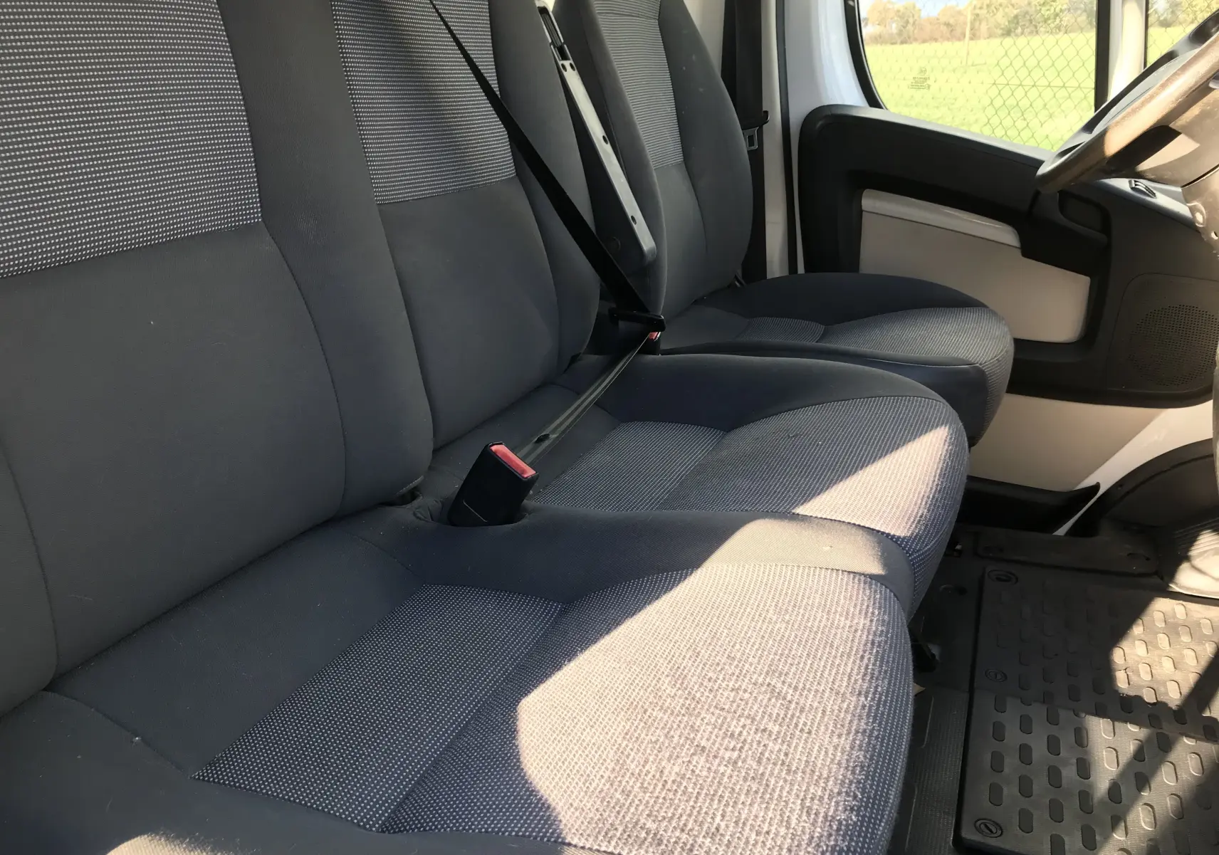 Intérieur du Peugeot Boxer 2014, vue côté gauche sur la banquette avant grise et le siège conducteur.