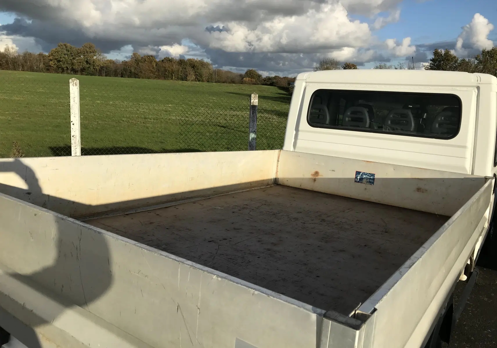 Vue arrière droite d'un plateau blanc du Peugeot Boxer Châssis Double Cabine 7 places, avec cabine visible et plateau vide.