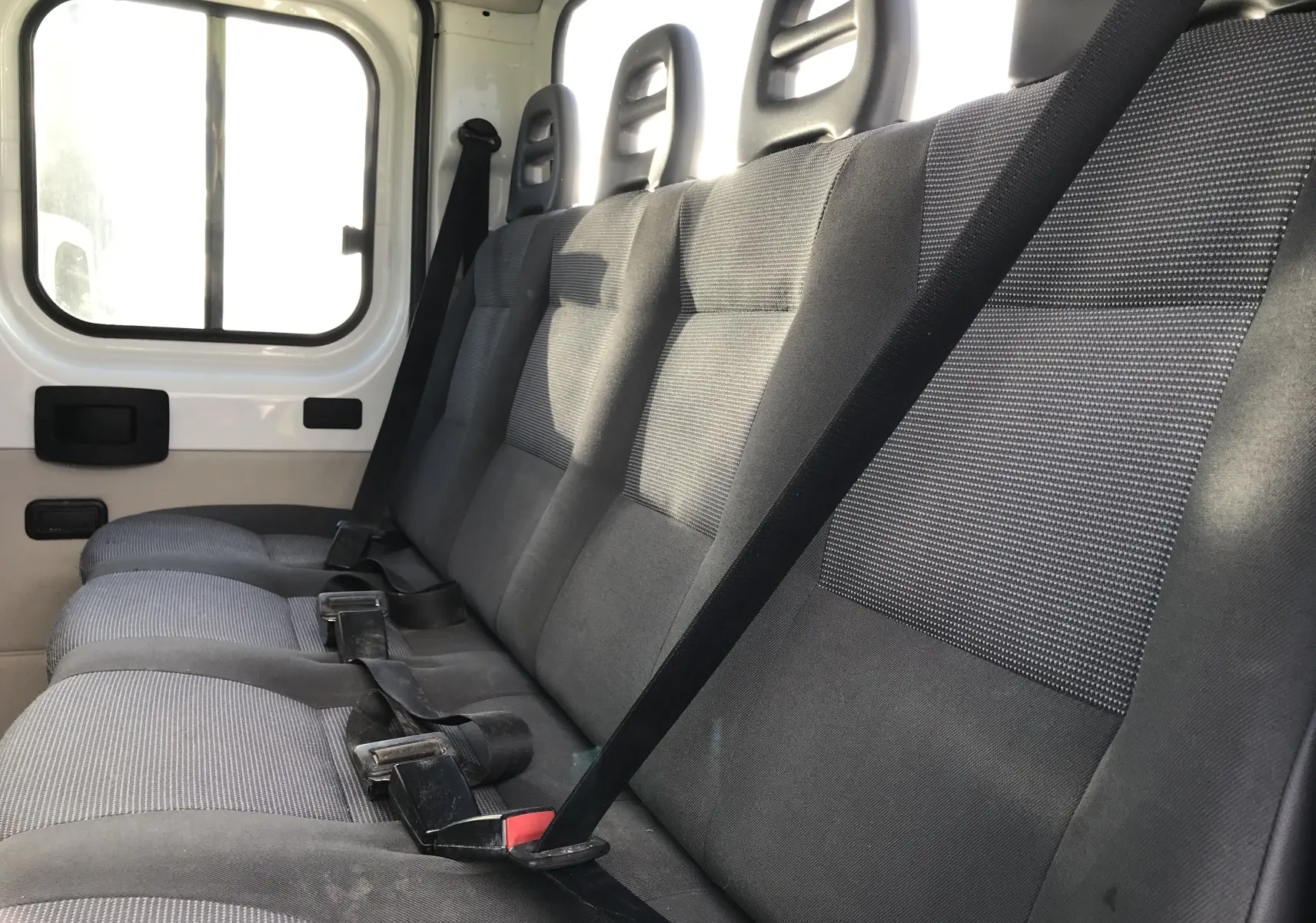 Vue intérieure côté droit des sièges arrière gris du Peugeot Boxer Chassis Double Cabine blanc de 2014, version 7 places.