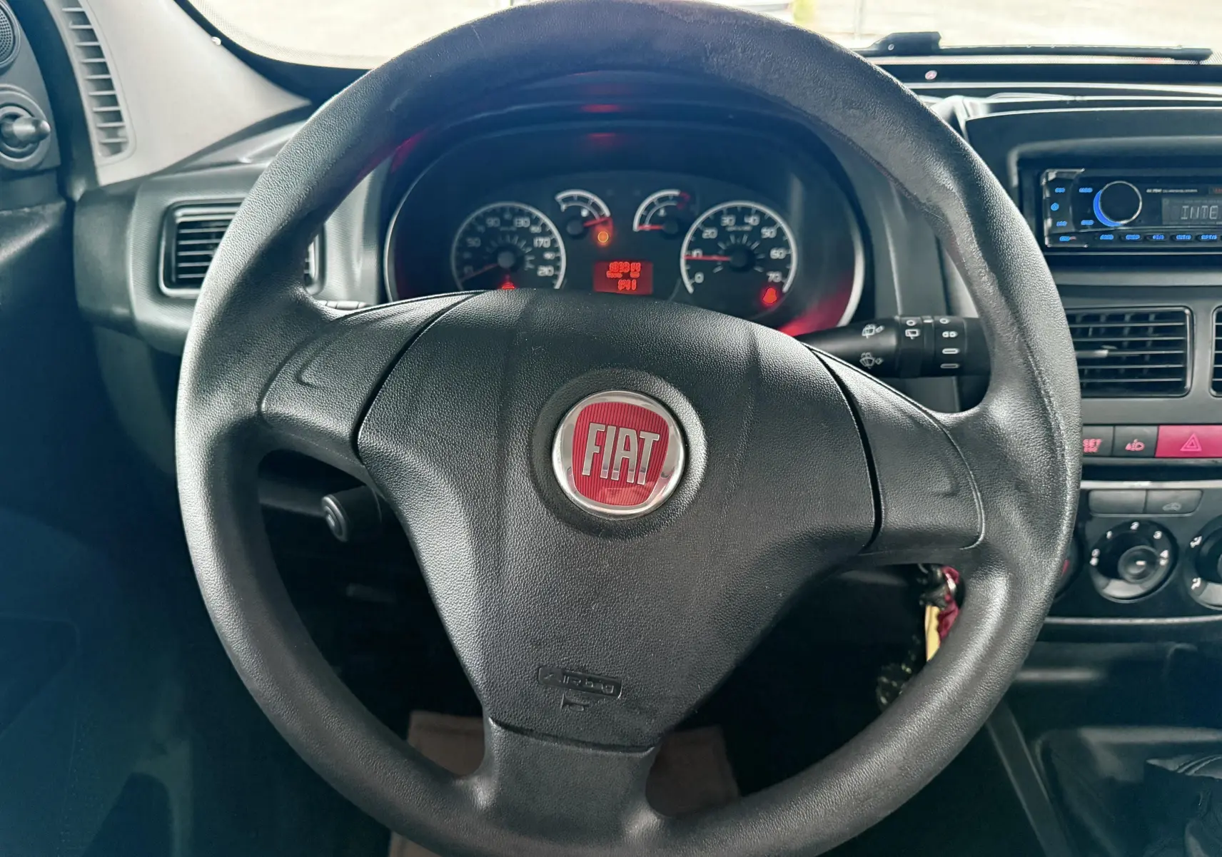 Vue rapprochée du volant noir avec logo FIAT rouge du tableau de bord du Fiat Doblo Cargo 2011.