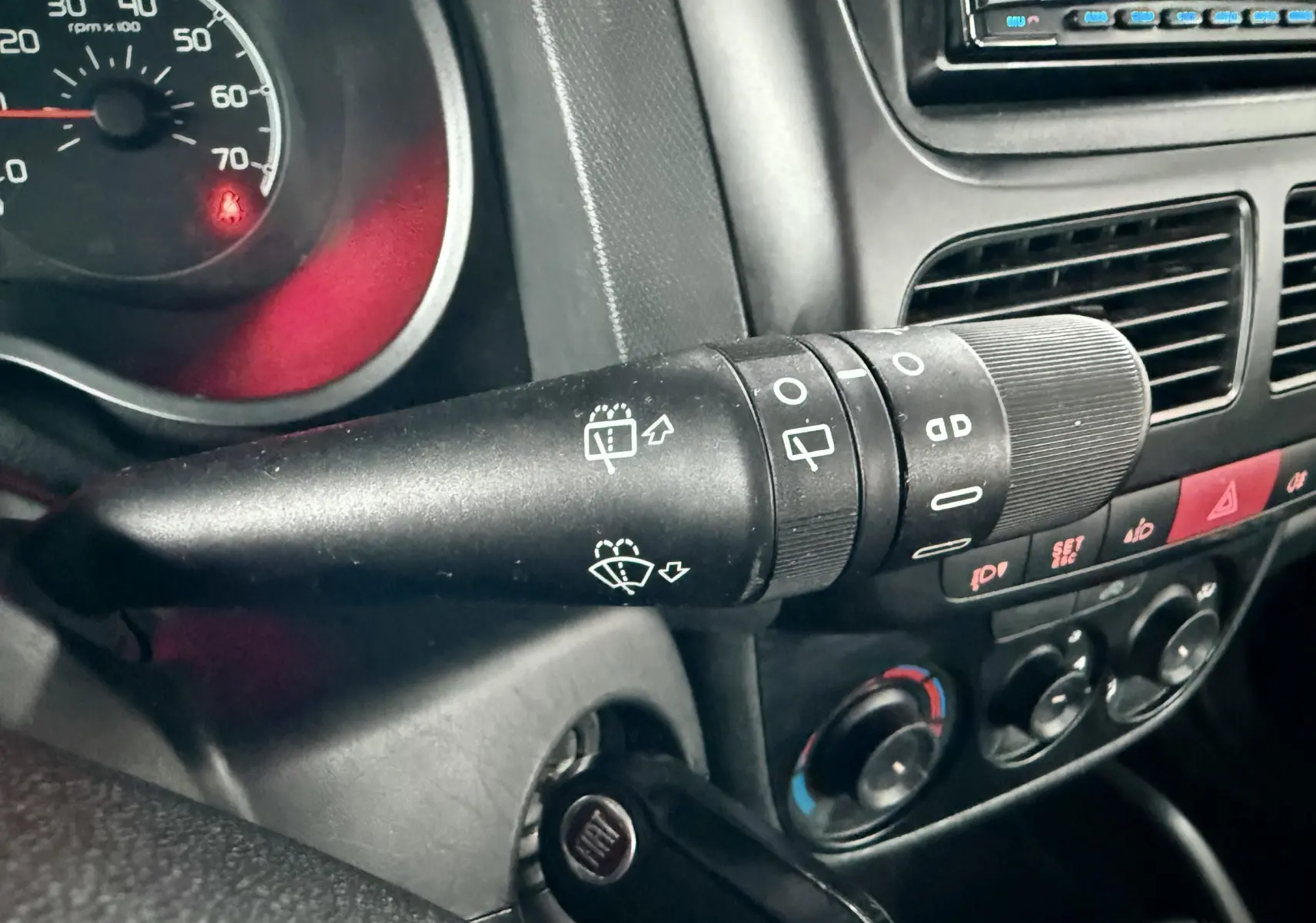 Gros plan sur la commande d’essuie-glace à gauche du volant dans l’habitacle noir du Fiat Doblo Cargo 2011.