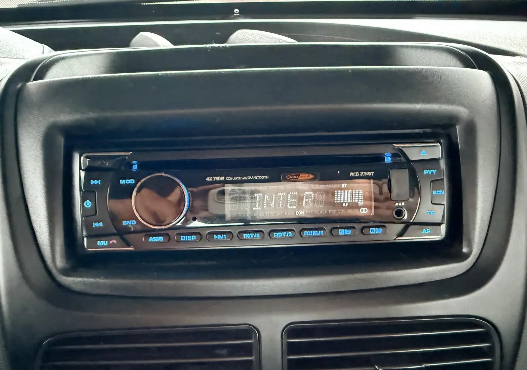 Gros plan sur la radio numérique intégrée au tableau de bord noir du Fiat Doblo Cargo rouge de 2011.