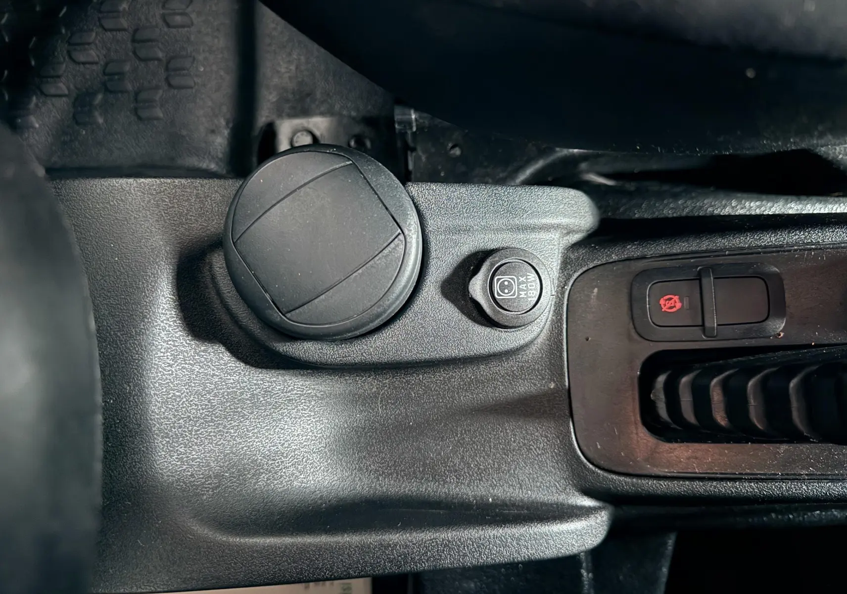 Détail de la console centrale noire du Fiat Doblo Cargo 2011 montrant prise 12V et bouton de verrouillage central.