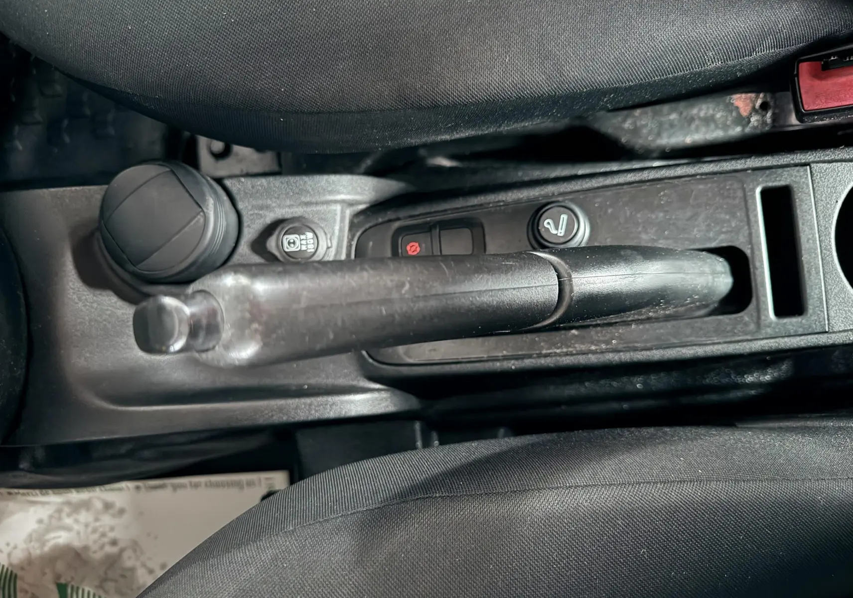 Vue rapprochée de la poignée de frein à main et console centrale noire du Fiat Doblo Cargo 2011.