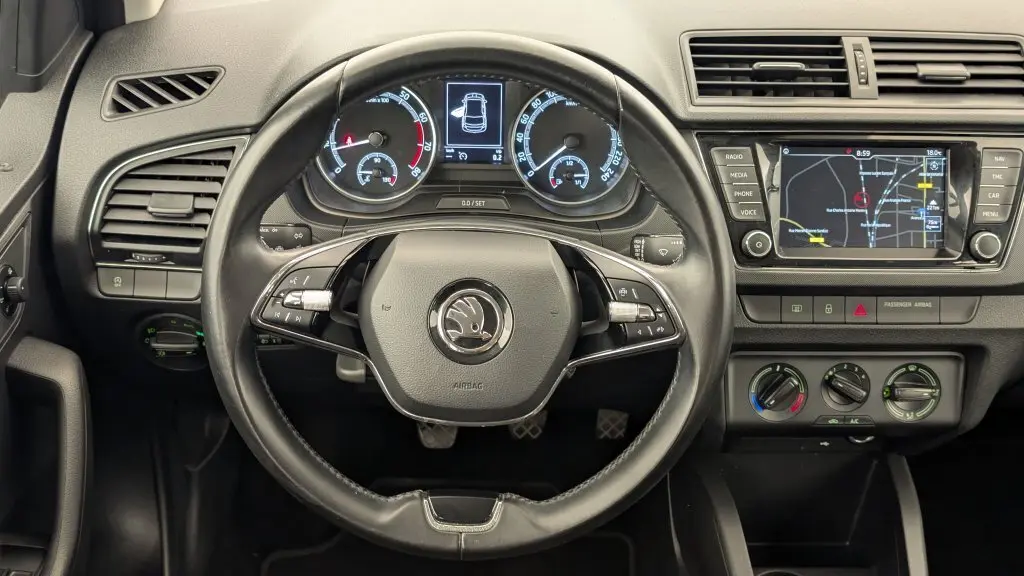 Vue intérieure centrée sur le volant et le tableau de bord de la Skoda Fabia Business 2020 avec écran de navigation allumé.