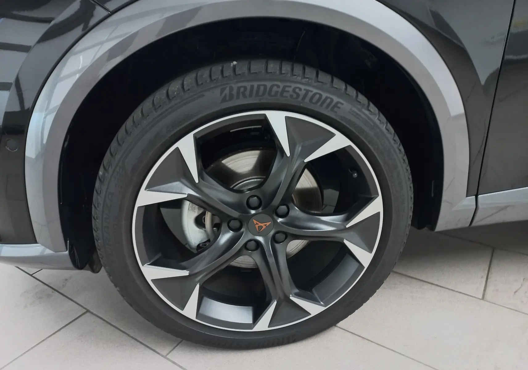 Gros plan sur la roue avant droite du CUPRA Formentor Noir Minuit avec jante alliage noire et argentée au design sportif.