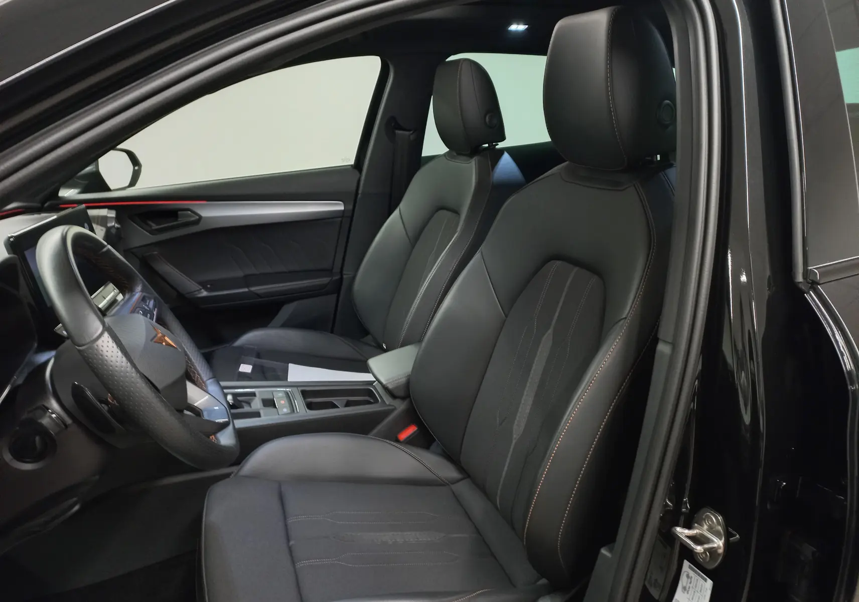 Vue intérieure côté conducteur du CUPRA Formentor 1.5 TSI 150 DSG7 VZ-LINE 2023 avec sièges noirs et coutures orange.