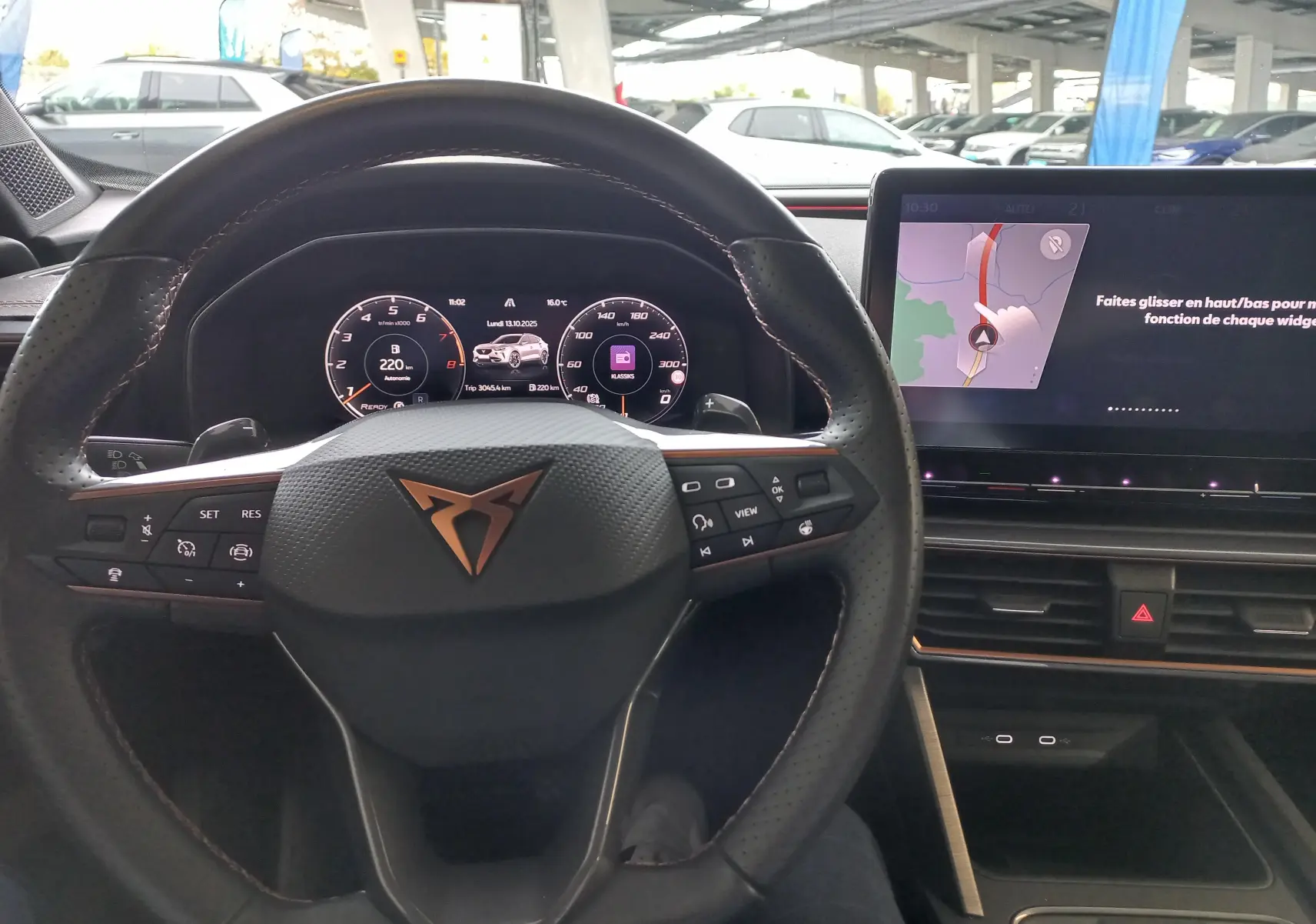 Vue intérieure centrée sur le volant CUPRA et le tableau de bord numérique avec écran tactile et finitions noires.
