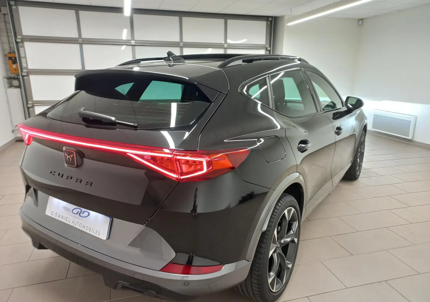 Vue 3/4 arrière droite d'un CUPRA Formentor noir minuit 2023 avec feux arrière LED et jantes alliage distinctives.