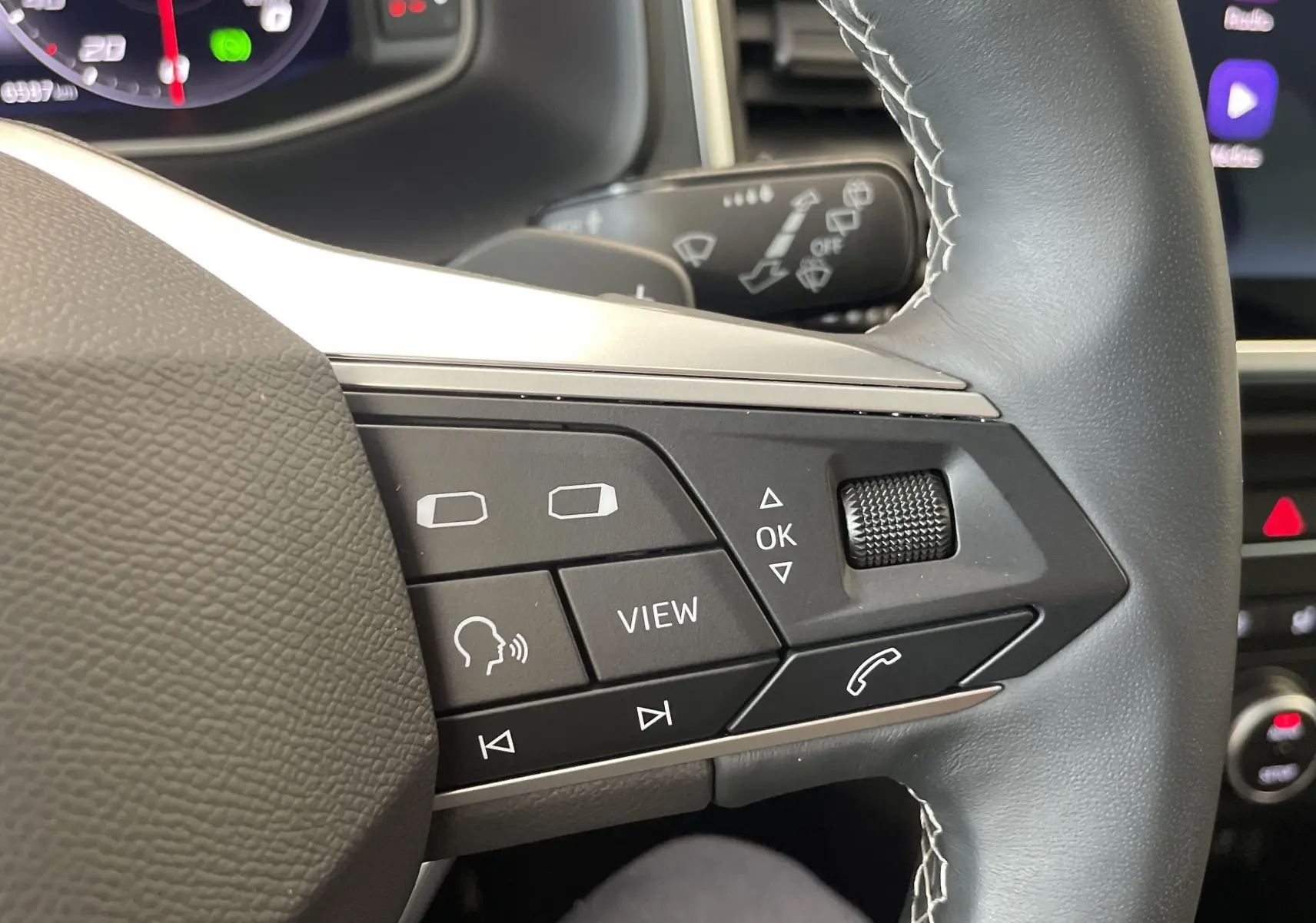 Gros plan sur les commandes multifonctions à droite du volant du SEAT Ateca 2024, intérieur moderne et écran tactile visible.