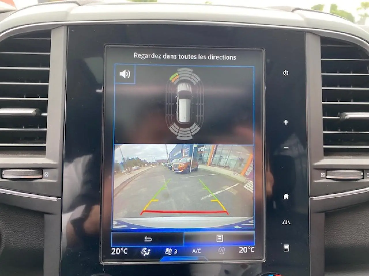 Écran central du Renault Koleos 2019 blanc montrant la caméra de recul et les capteurs de stationnement.