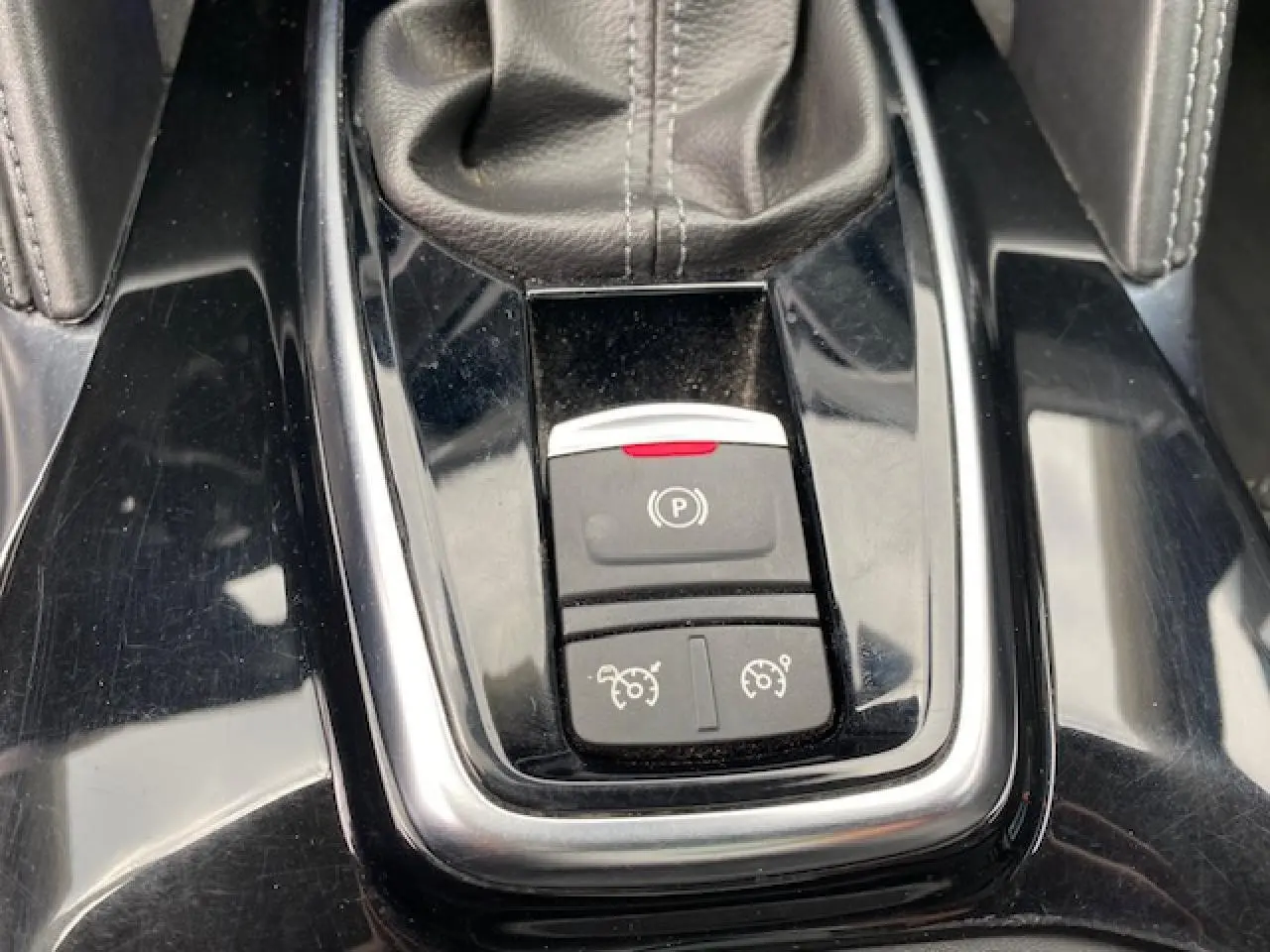 Gros plan sur la console centrale noire du Renault Koleos blanc 2019, montrant le frein à main électronique et commandes de régulateur.