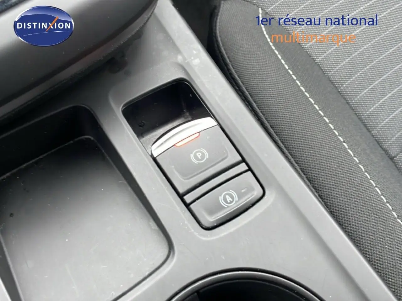 Gros plan sur la console centrale du Renault Arkana 2025, montrant les boutons de frein à main électronique et auto hold, intérieur tissu noir.