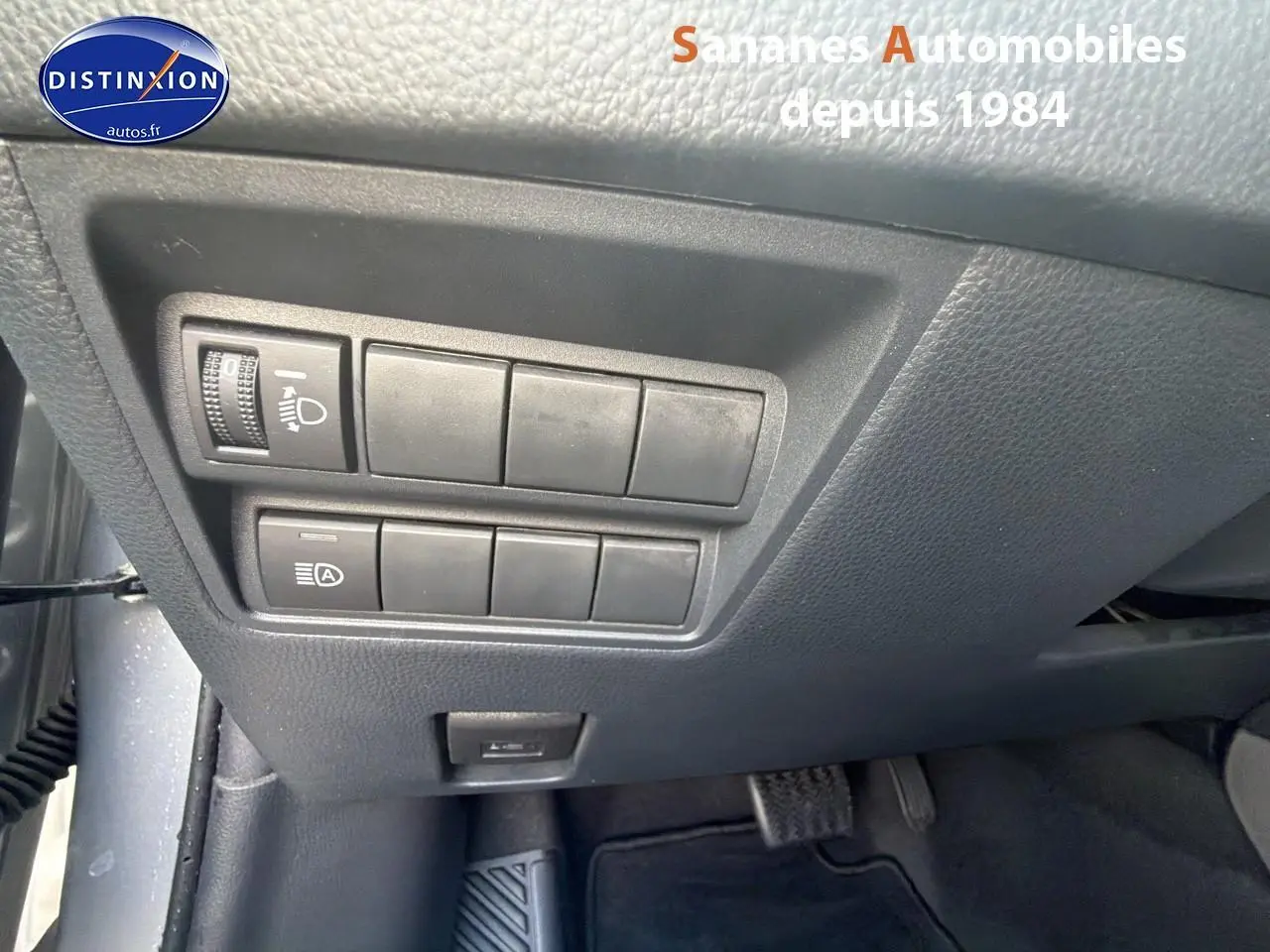 Vue rapprochée des commandes d’éclairage et d’assistance situées sous le tableau de bord côté conducteur de la Toyota Yaris Hybrid 2023 gris métallisé.