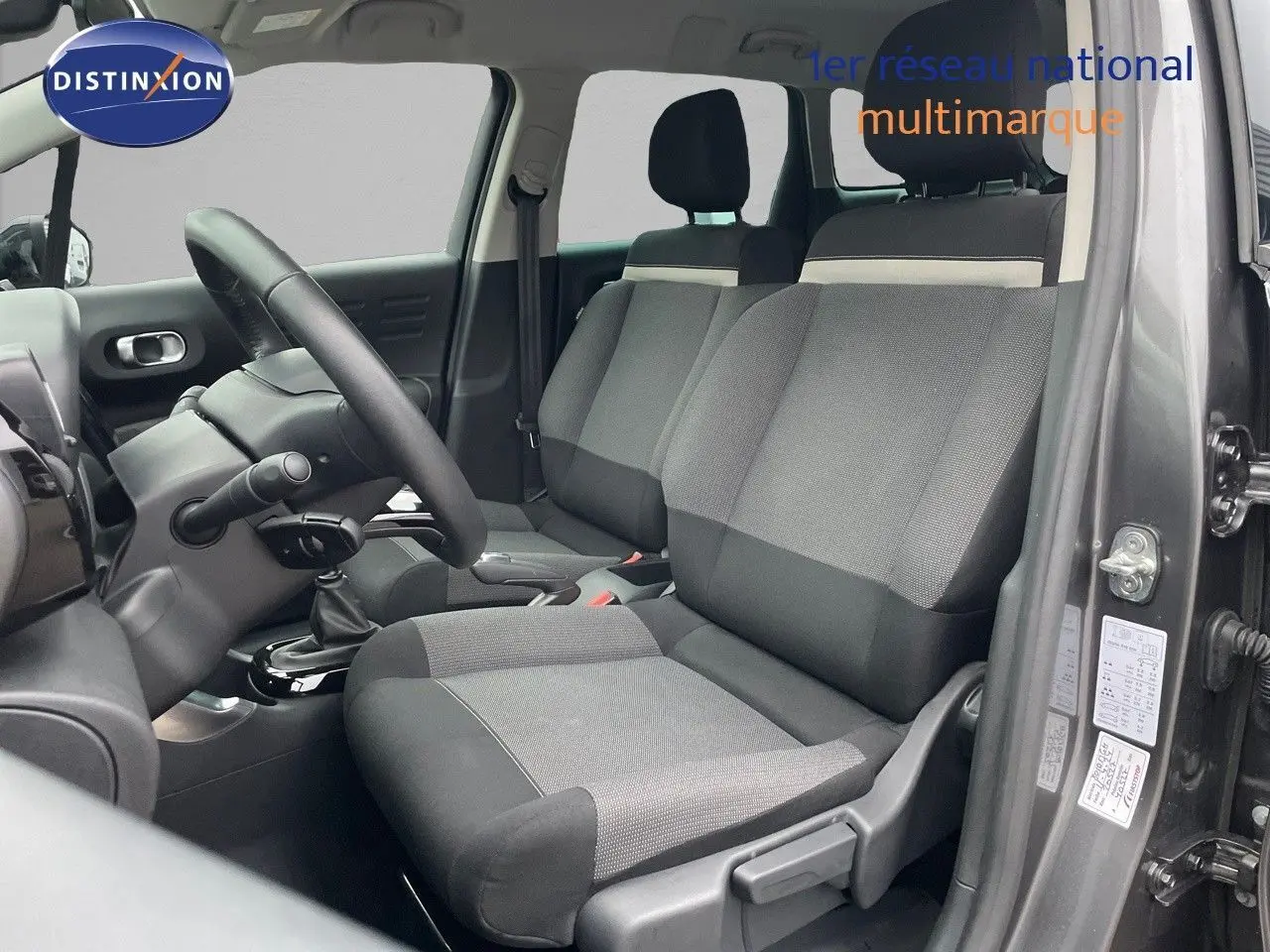 Vue intérieure côté conducteur du Citroën C3 Aircross gris platinium, montrant les sièges en tissu gris et noir.