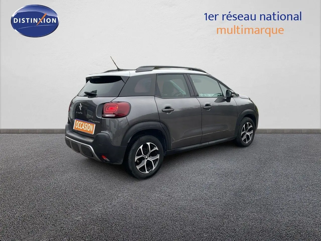 Vue 3/4 arrière droite d'une Citroën C3 Aircross gris platinium métal avec jantes bi-ton et toit noir.