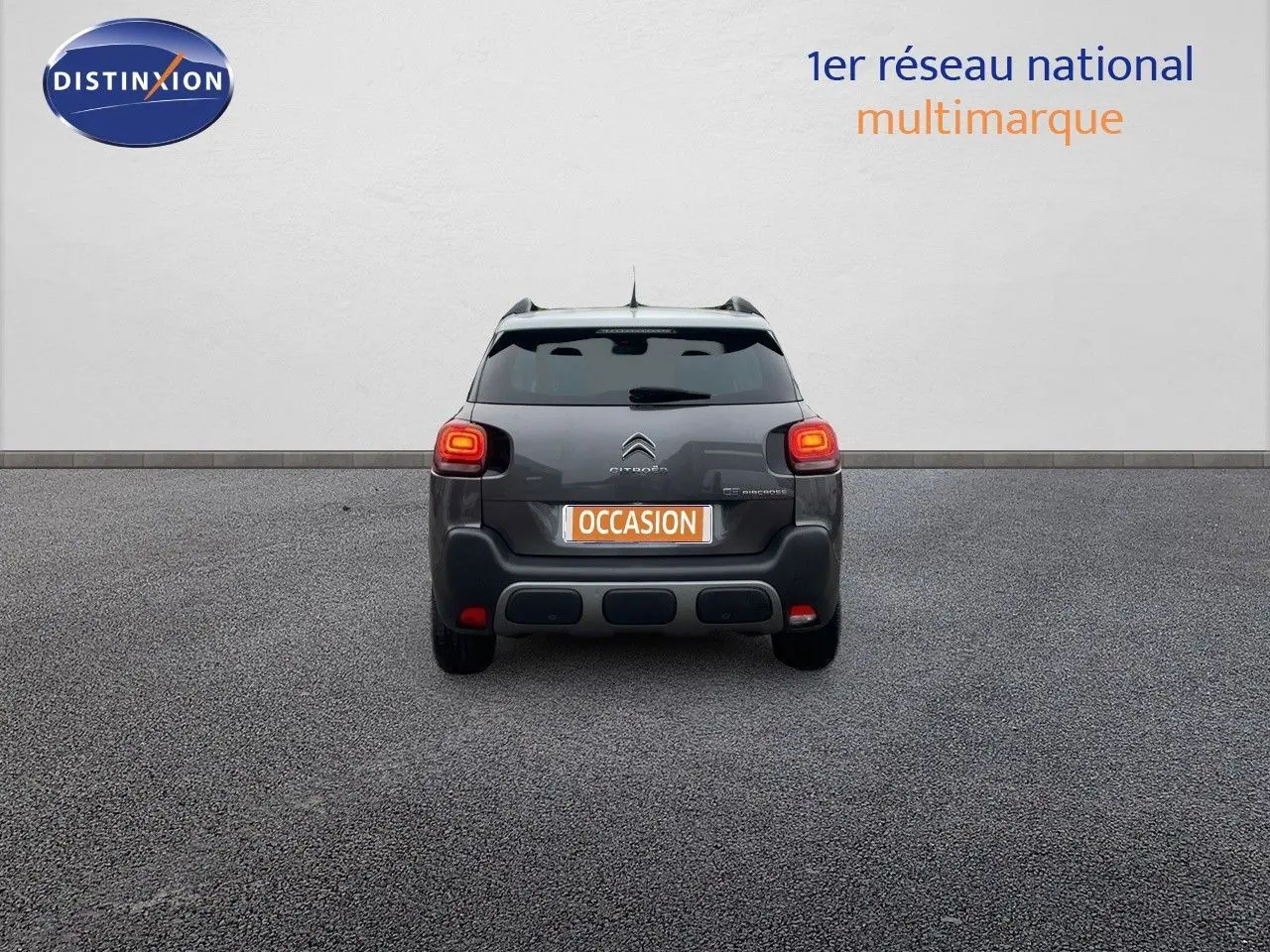 Vue arrière d'un Citroën C3 Aircross gris platinium métal avec feux allumés sur fond neutre.