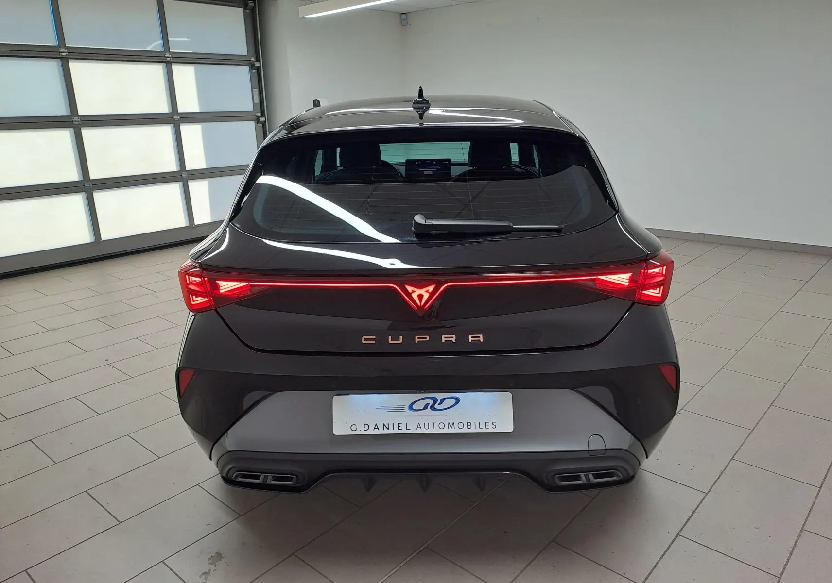 Vue arrière d'une CUPRA Leon Ph.2 noir minuit avec feux LED reliés et double sortie d'échappement intégrée.