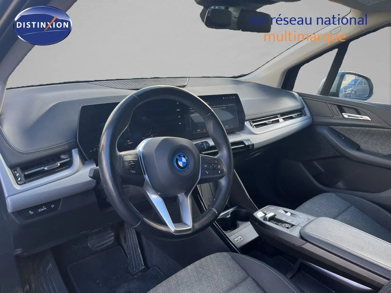Vue intérieure côté conducteur de la BMW Série 2 Active Tourer 225e XDrive 2022 avec tableau de bord moderne et sièges gris.