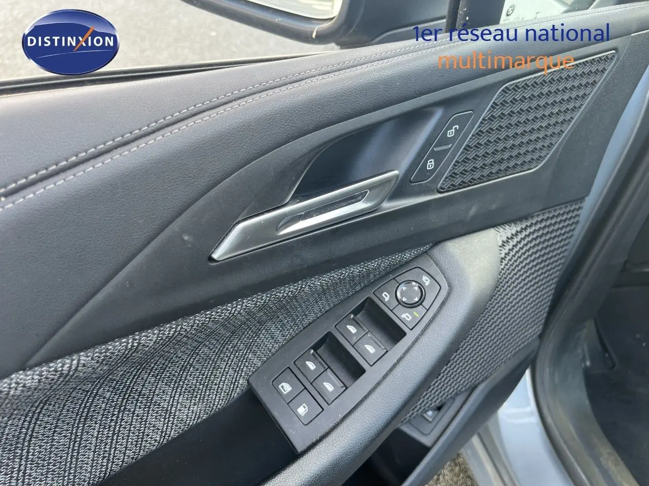 Gros plan sur la porte avant gauche de la BMW Série 2 Active Tourer 225e XDrive, avec garniture tissu et commandes électriques.