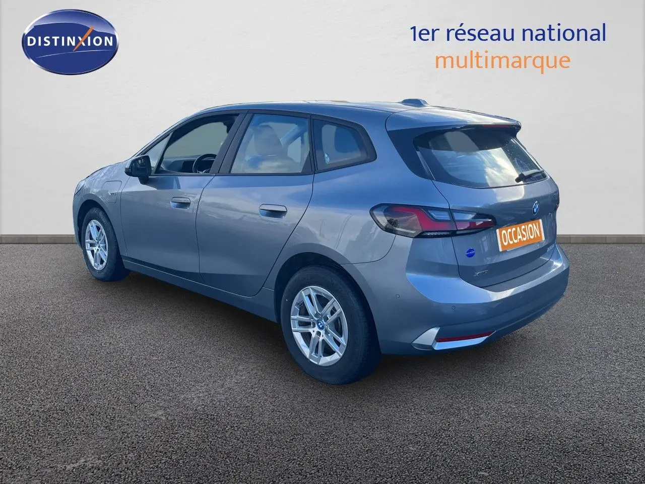 Vue 3/4 arrière droite d'une BMW Série 2 Active Tourer 225e xDrive grise métallisée avec jantes alliage et logo occasion.