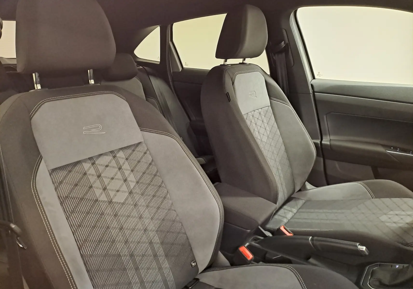 Intérieur du Volkswagen Taigo 2024, vue côté droit sur les sièges R-Line en tissu gris avec surpiqûres contrastées.