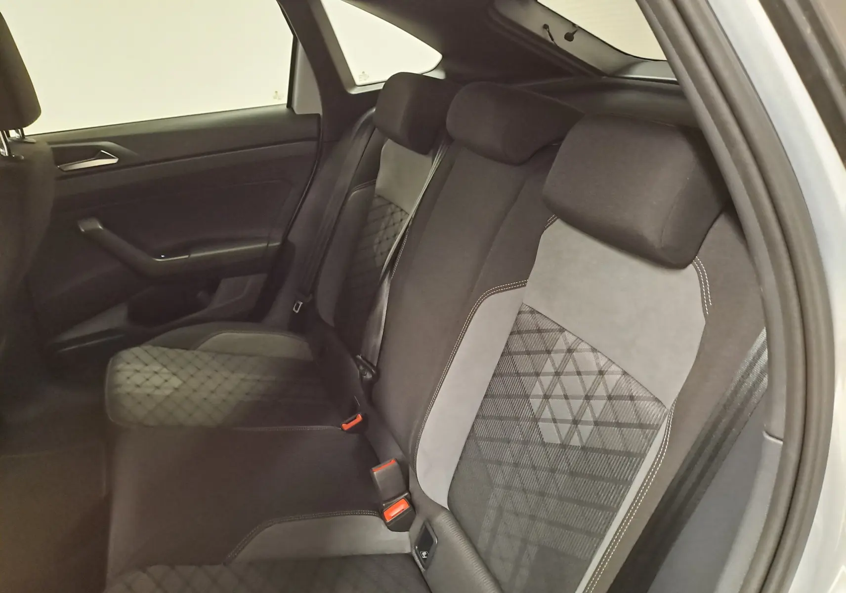 Vue intérieure des sièges arrière en tissu noir et gris du Volkswagen Taigo 2024, côté droit ouvert.