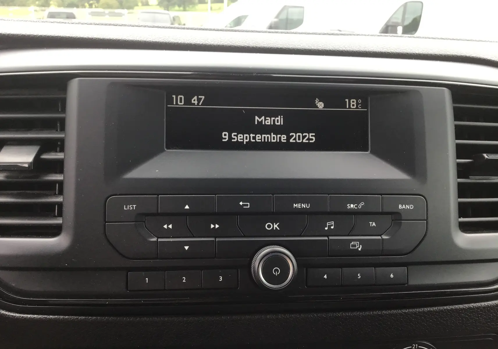 Affichage central de la console multimédia de l'Opel Vivaro blanc, avec écran digital et commandes tactiles visibles.