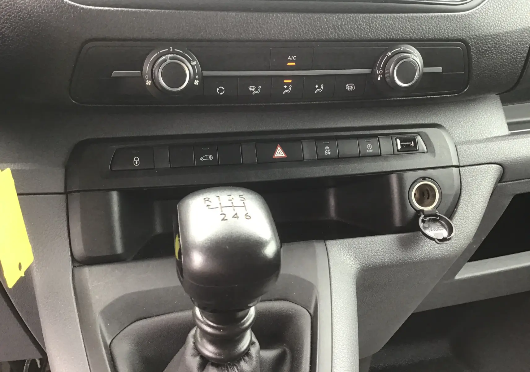 Gros plan sur la console centrale de l'Opel Vivaro blanc 2022, mettant en valeur le levier de vitesses manuel et les commandes climatiques.