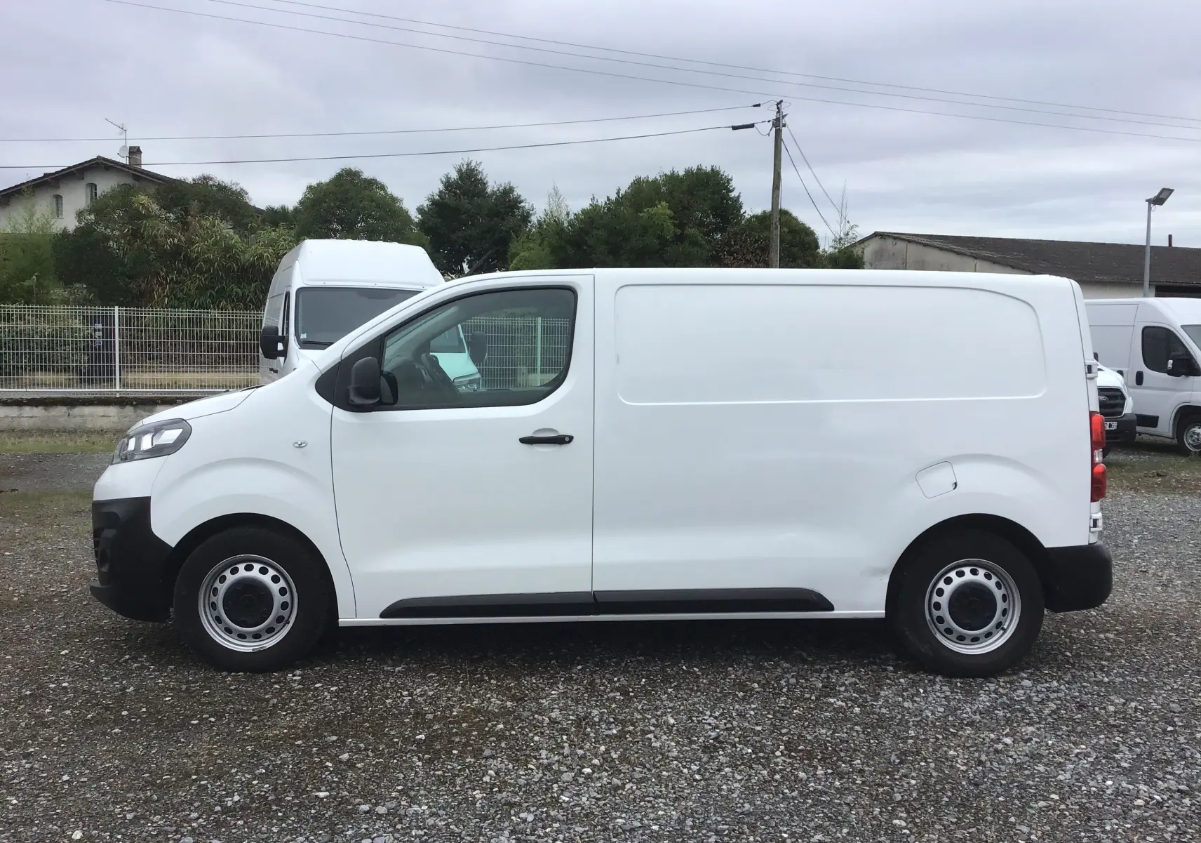 Vue de profil côté gauche d'un utilitaire Opel Vivaro blanc 2022 avec jantes acier et porte latérale coulissante.