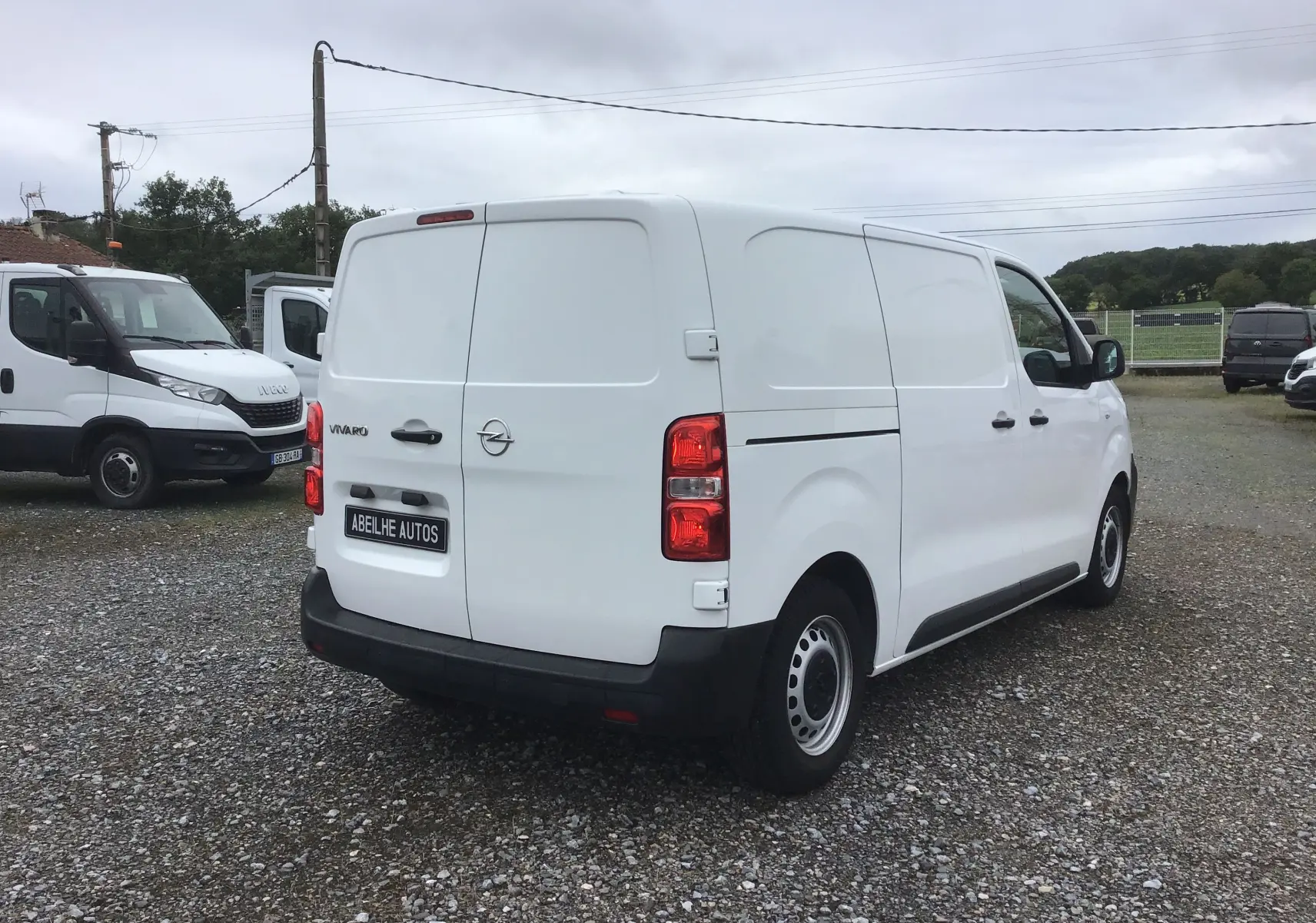 Vue 3/4 arrière droite d'un utilitaire Opel Vivaro blanc de 2022 avec portes arrière battantes et jantes acier noires.