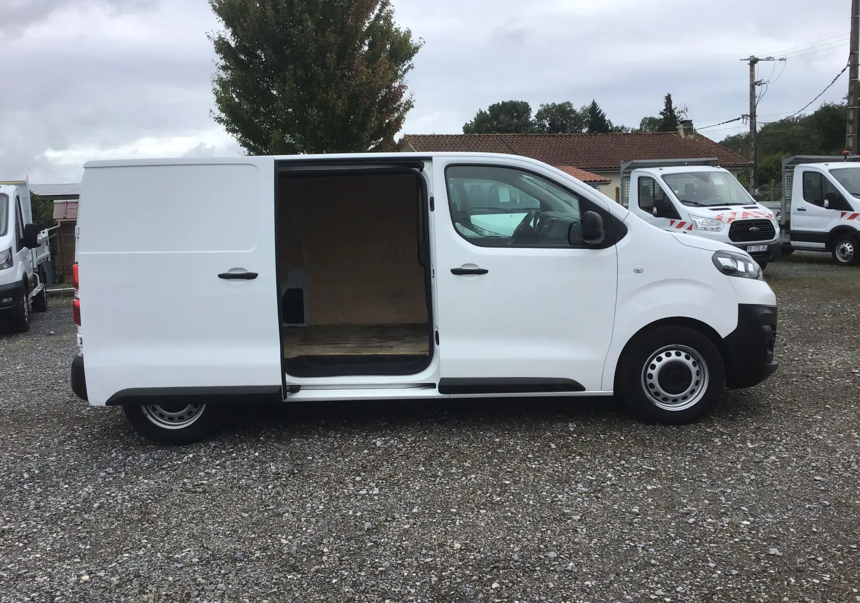 Vue de profil côté droit d'un Opel Vivaro blanc 2022 avec porte latérale coulissante ouverte montrant l'espace de chargement.