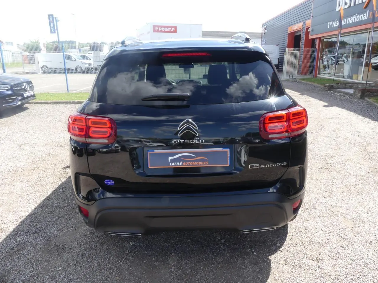 Vue arrière d'un Citroën C5 Aircross noir avec feux arrière LED et logo distinctif sur un parking extérieur.