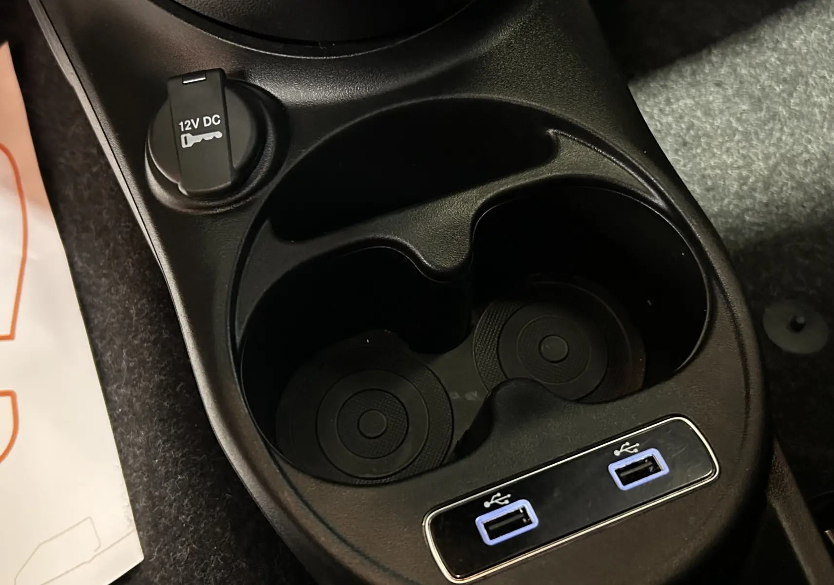 Gros plan sur la console centrale noire de la Fiat 500 2023 avec porte-gobelets et deux ports USB bleus.