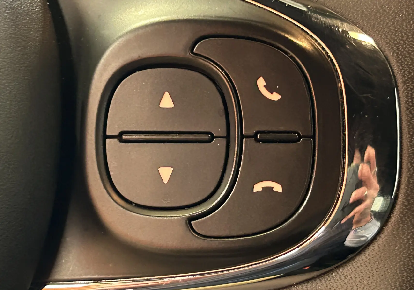 Gros plan sur les commandes noires du volant de la Fiat 500 2023 finition Pack Confort, avec boutons de gestion d'appels.