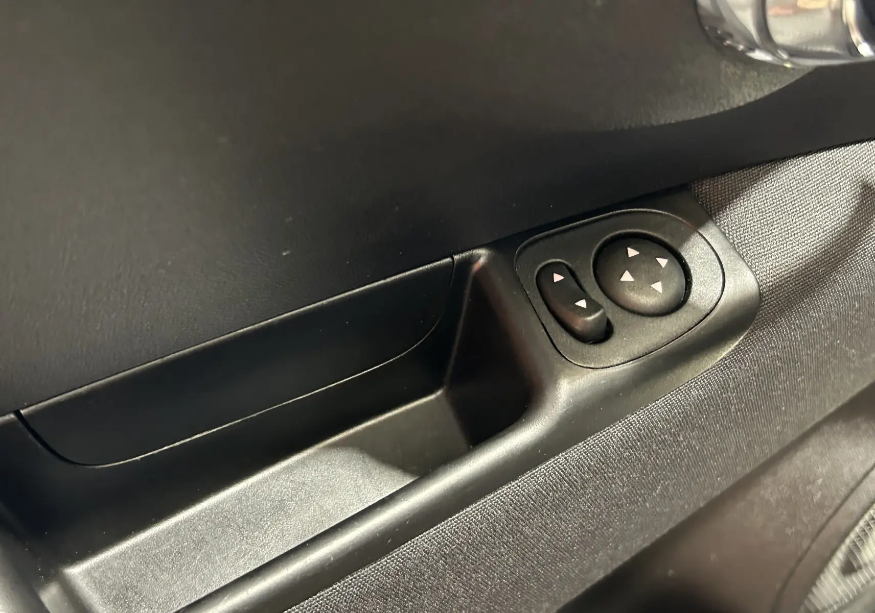 Gros plan sur les commandes de réglage des rétroviseurs côté gauche d'une Fiat 500 noire de 2023.