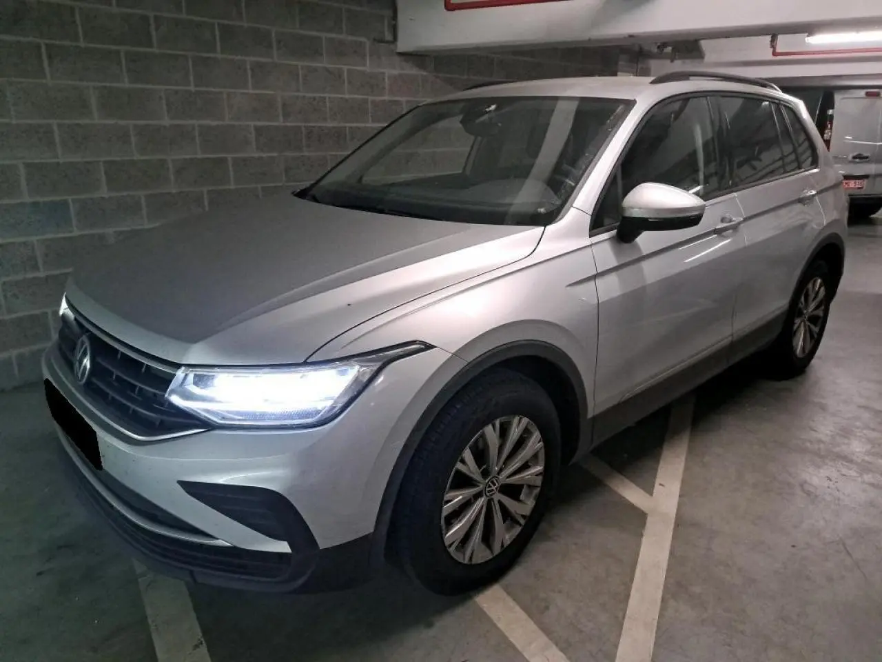 Volkswagen Tiguan 2.0 TDI 150 DSG7 Life argent fleuret en 3/4 avant droit avec feux LED allumés dans un parking.