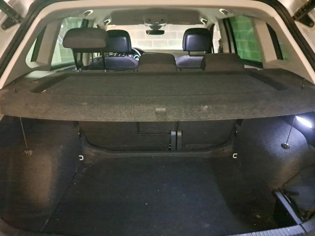 Vue intérieure du coffre ouvert du Volkswagen Tiguan 2.0 TDI 150 DSG7 Life argent, montrant l'espace de chargement et la plage arrière.