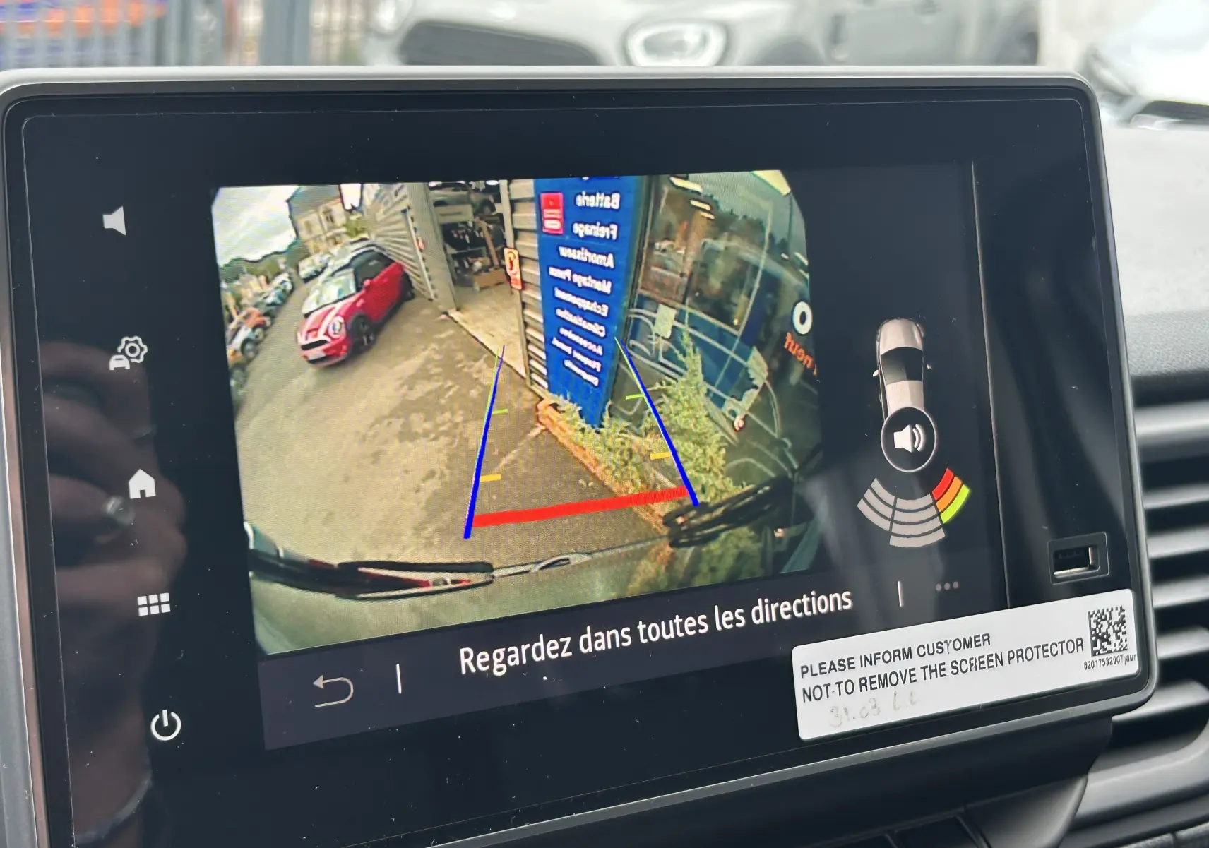 Écran de la caméra de recul du Renault Trafic Combi blanc, affichant les lignes de guidage et l'environnement arrière.